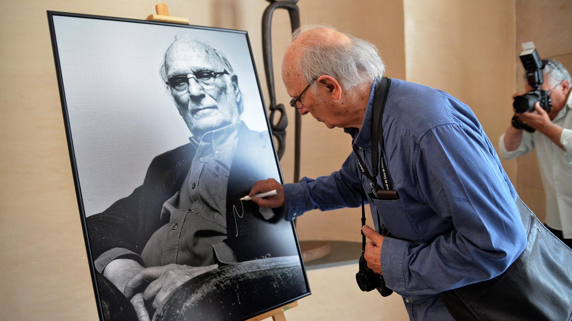Carlos Saura realizando la tradicional firma de su retrato