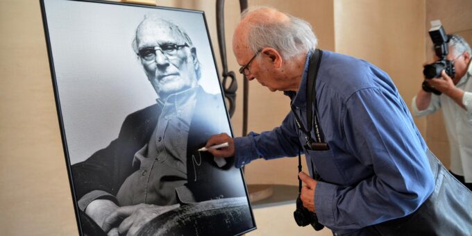 Carlos Saura realizando la tradicional firma de su retrato